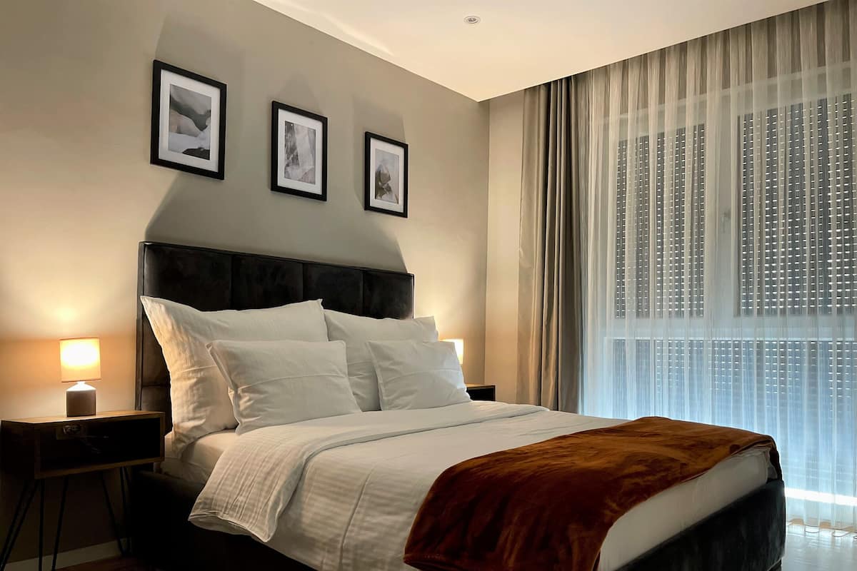 Une chambre d’hôtel moderne avec un grand lit, une table de chevet avec une lampe et trois tableaux encadrés au mur.