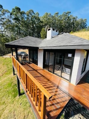 A modern house with a wooden deck and large windows. - Chales Cabana (Camanducaia)