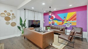 A modern living room with a brown leather sofa, a coffee table, and a TV. - Blue Lagoon Spanish Retreat 5BRs and Pool Airport (Houston)