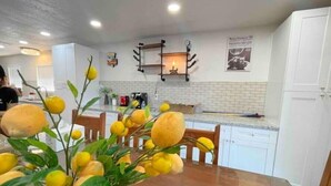 A kitchen with white cabinets, a wooden dining table, and a decorative lemon plant. - Blue Lagoon Spanish Retreat 5BRs and Pool Airport (Houston)