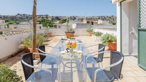 A rooftop terrace with a glass table, chairs, and potted plants. - Gaia Verde by Interhome (San Vito lo Capo)