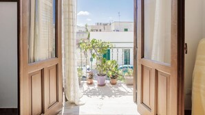 An open door leading to a balcony with potted plants and a view of buildings. - Gaia Verde by Interhome (San Vito lo Capo)