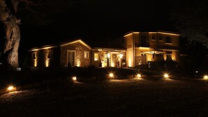 A two-story house with a stone facade, multiple windows, and a well-lit entrance. - Tenuta Bellelli (Castellabate)