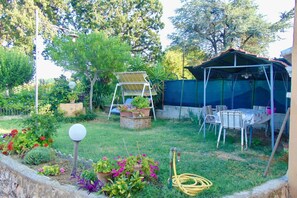 Un jardin avec une table et des chaises, un panneau solaire et un espace abrité.