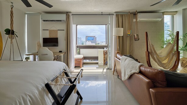 Une chambre d’hôtel moderne équipée d’un lit, d’un canapé, d’un bureau et d’un balcon offrant une vue sur la ville.