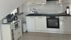 A modern kitchen with white cabinets, a black countertop, and a built-in oven.