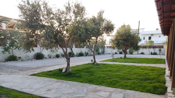 Un cortile con un vialetto in pietra, erba verde e alberi.