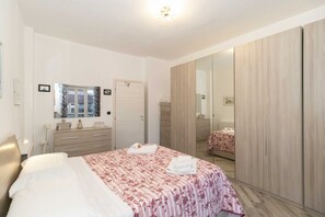 Camera da letto con letto, comò, specchio, armadio e vista esterna.