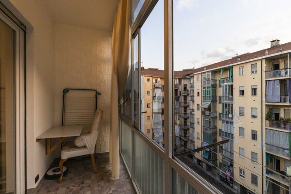 Ein Balkon mit einem Stuhl, einem kleinen Tisch und Blick auf benachbarte Gebäude.