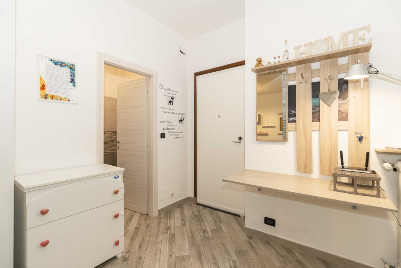 Ein Zimmer mit einem weißen Schminktisch, einem Spiegel mit der Aufschrift 'HOME' und einem Holzregal mit einer Lampe.
