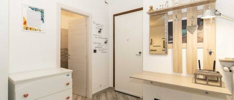 Ein Zimmer mit einem weißen Schminktisch, einem Spiegel mit der Aufschrift 'HOME' und einem Holzregal mit einer Lampe.