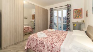 A bedroom with a bed, a wardrobe, a radiator, and a window with curtains.