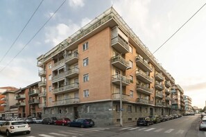 Un edificio residenziale a più piani con balconi, auto parcheggiate e cielo sereno.