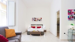 A bedroom with a bed, a bedside table, a nightstand, a glass table, and a window. - GuestHost - Veiled Christ Bilo Apartment (Napoli)