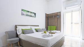Ein ordentlich eingerichtetes Schlafzimmer mit Bett, Kissen, einem Stuhl, einer Holzvertäfelung und einer Tür.