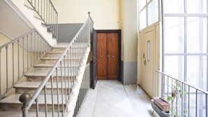 Eine Treppe mit Metallgeländern, eine Holztür am Fußende und ein Blumentopf rechts.