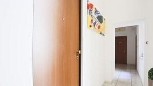 Ein Flur mit Holztür, Fliesenboden und einem Bild an der Wand.