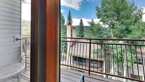 A balcony with a metal railing overlooking a residential area with trees and houses. - 🌲Timberline 303 Studio Loft Standard ~ Hot Tub~Pool~WiFi~Ski-in/out~Local Shuttle🌲 (Snowmass Village)
