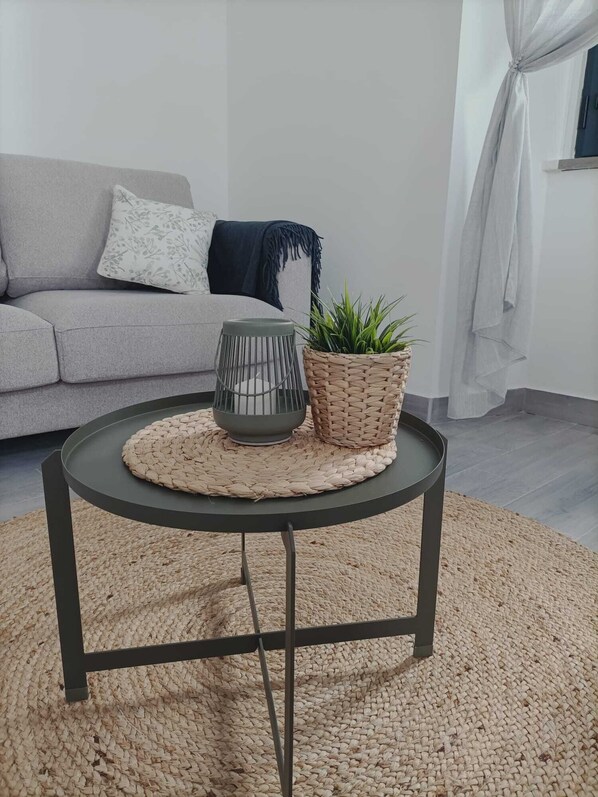 A round table with a woven placemat, a grey bowl, and a woven basket with a plant. - Zostera Marina (Olhão)