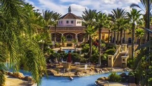 A resort with a swimming pool, palm trees, and a building with a dome roof.