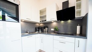 A modern kitchen with white cabinets, a black countertop, and a built-in stove. - Relax in our (Losheim am See)