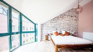 A modern bedroom with a large bed, a brick-patterned wall, and a view through large windows. - Relax in our (Losheim am See)