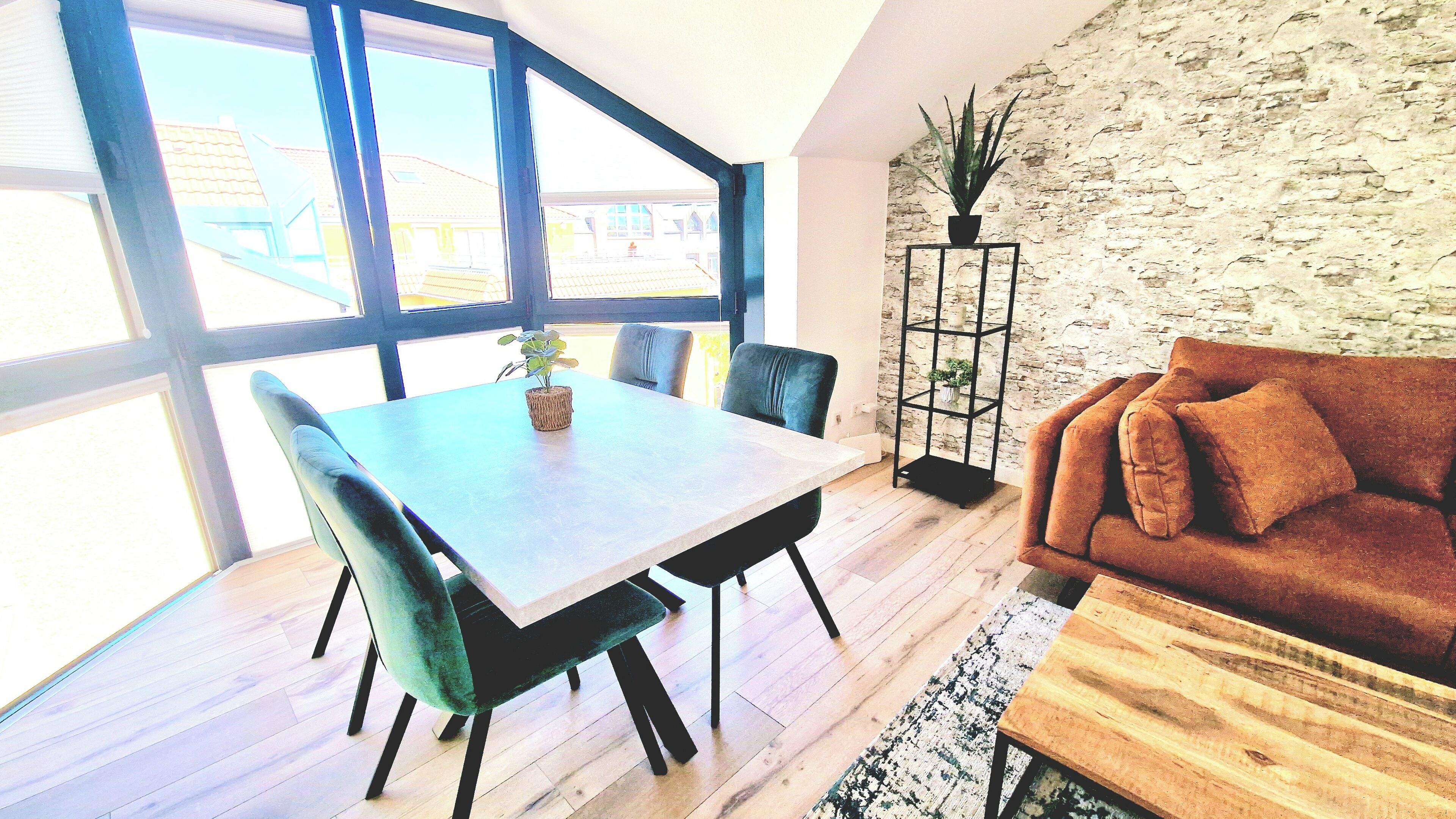 Un salon moderne avec une table à manger en bois, deux chaises, un canapé et une plante en pot.