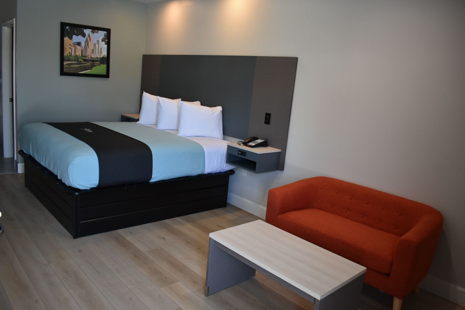 Una moderna camera d'albergo con un letto, un comodino e una poltrona rossa.