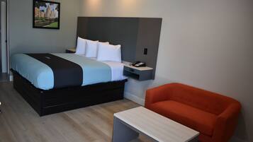 Una moderna camera d'albergo con un letto, un comodino e una poltrona rossa.