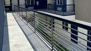 A modern building with a covered outdoor area, metal railings, and a clear sky. - Bluestar Inn (Houston)