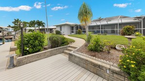 Une maison moderne dotée d’un patio couvert, d’une piscine et d’un jardin bien entretenu.