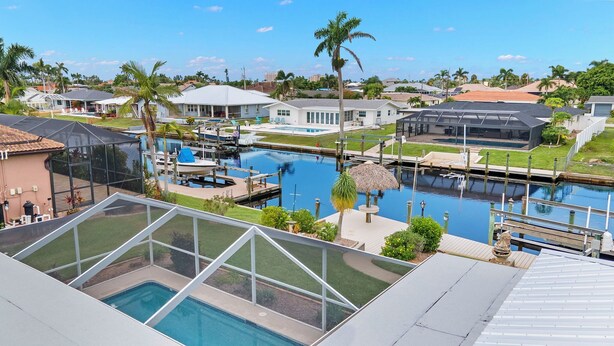 Un quartier résidentiel doté d’une grande piscine, d’un quai avec des bateaux et de maisons aux toits de différents styles.