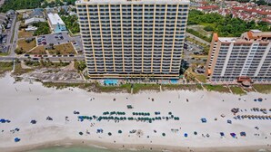 Un hôtel de grande hauteur doté d’une piscine, situé en bord de mer et offrant des parasols sur la plage.