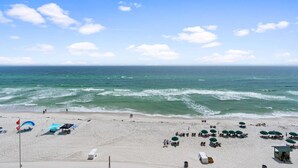 Une plage avec des parasols, des chaises longues et un poste de surveillance pour les sauveteurs.