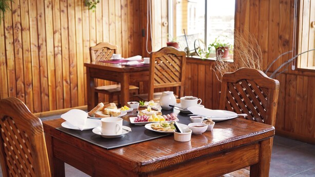 Un tavolo da pranzo in legno con piatti di cibo, tazze e una brocca.