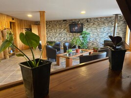 A modern hotel lobby with a stone wall, wooden accents, and a flat-screen TV mounted on the wall.