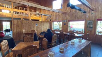 Un interior de madera con techos altos, varias mesas de comedor y sillas.