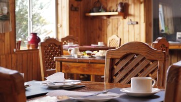 Una mesa de madera con sillas, platos y una taza.