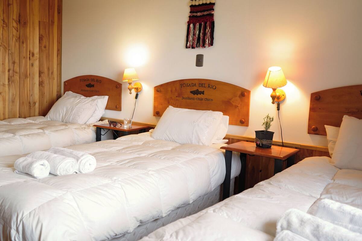 Ett hotellrum med två sängar, trägavlar och väggmonterade lampor.