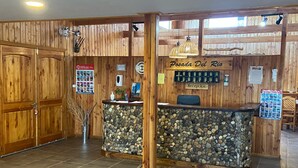 Una reception con pareti in pietra, pannelli in legno e un cartello che recita 'Posada Del Rio'.