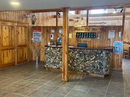 A reception desk with a stone wall, wooden paneling, and a sign reading "Posada Del Rio".