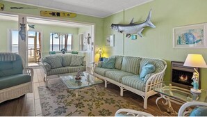 Een gezellige woonkamer met een open haard, gestreepte banken en een grote vis aan de muur.