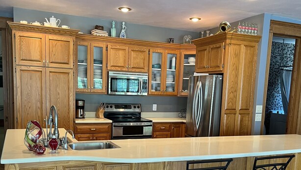 A modern kitchen with wooden cabinets, stainless steel appliances, and a large island with two bar stools.
