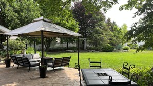 A patio with a table and chairs, a covered seating area, and a lawn.