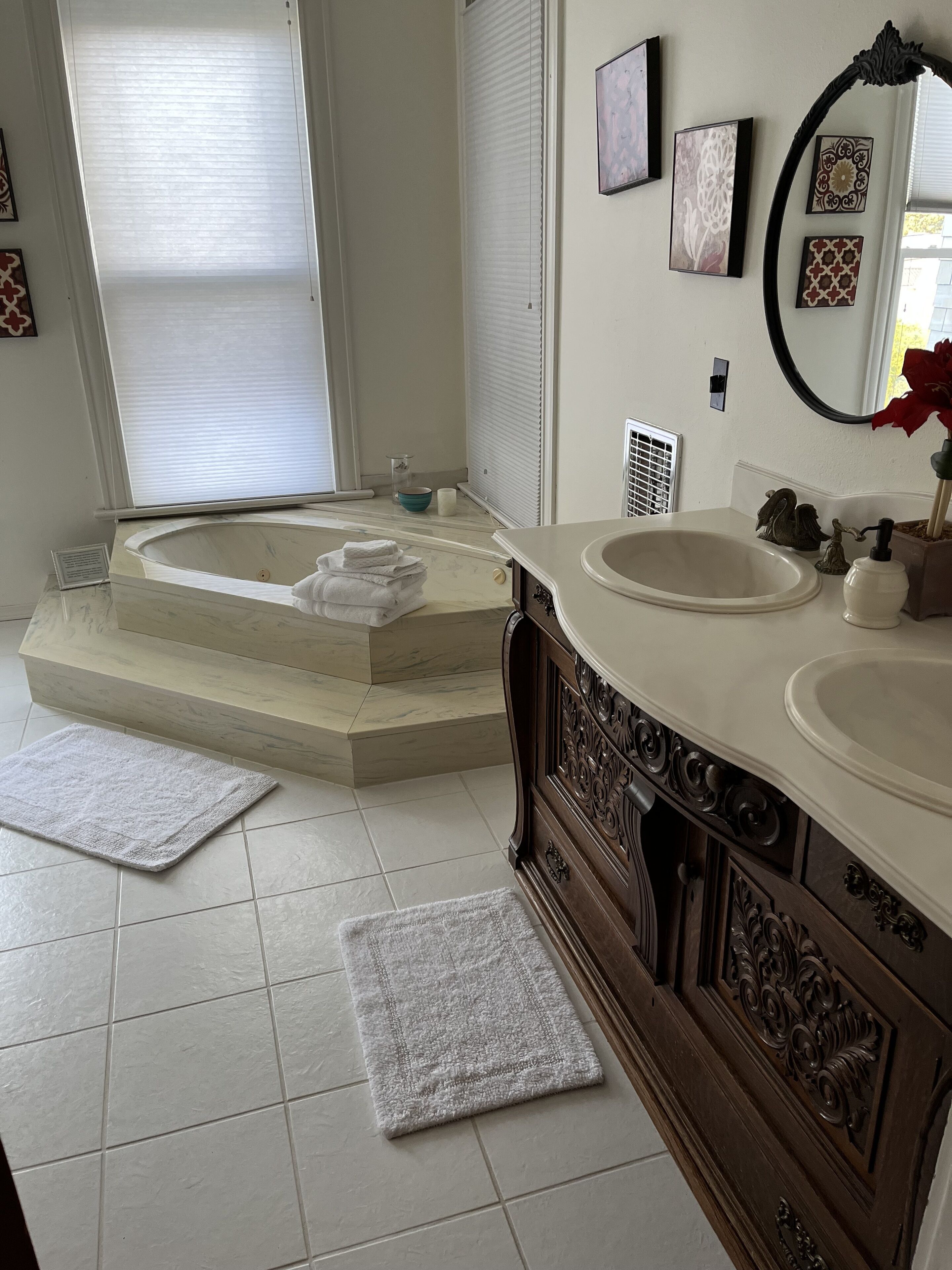 Ein Badezimmer mit einer freistehenden Badewanne, zwei Waschbecken, einem Waschtisch und Wanddekoration.