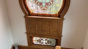 A wooden staircase with a stained glass window above.