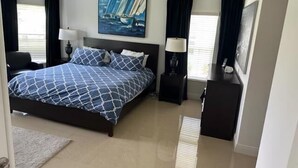 Un dormitorio con una cama, dos mesitas de noche, un cuadro y un escritorio con lámpara.