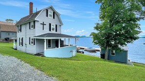 A two-story house with a porch and a small shed by the water. - Kineo Point (Waterfront on Moosehead Lake) (Rockwood)