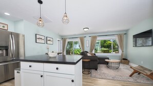 A modern kitchen with a central island, stainless steel appliances, and a large window with curtains. - Channel Charmer - Prime Gun Lake Waterfront Stay (Shelbyville)