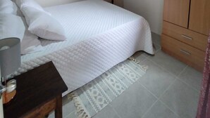 A bedroom with a bed, a bedside table, a fan, and a wardrobe.